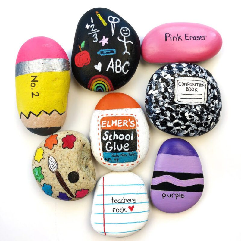Eight rocks are painted as various back-to-school items including a purple crayon, a pink eraser, and a pencil.
