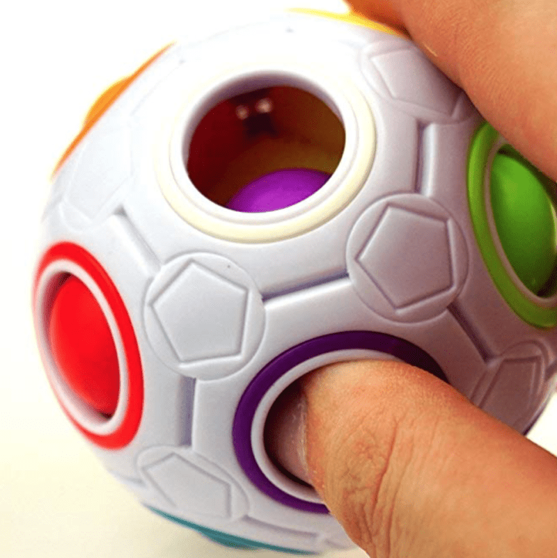 Student playing with a white plastic ball with holes filled with smaller colorful rubber balls