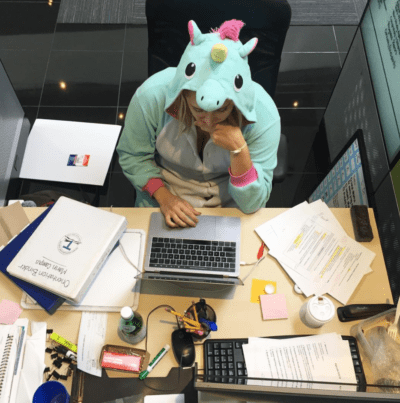 Educator in unicorn onesie working hard at her desk.