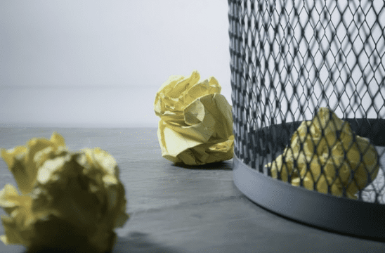 Rolled up paper balls next to trash can