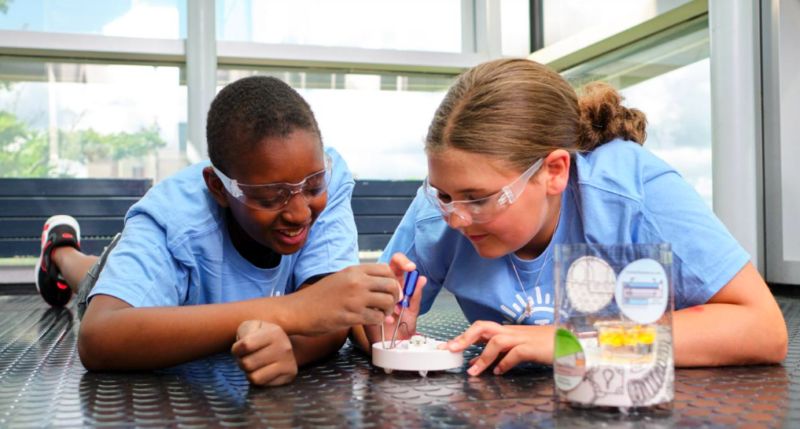 Two students wearing lab goggles for on a STEM project together