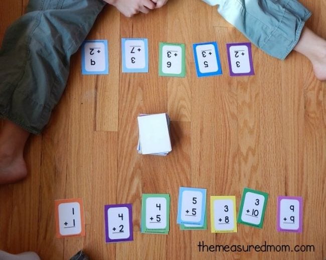cards with math facts on them on the floor with a stack of cards in the middle 