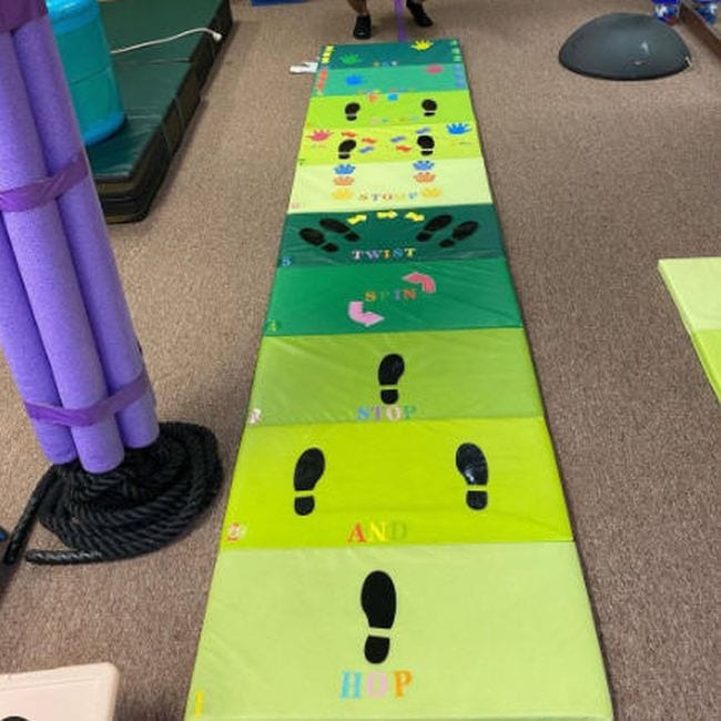 Foldable gym mat in shades of green marked with footprints and handprints