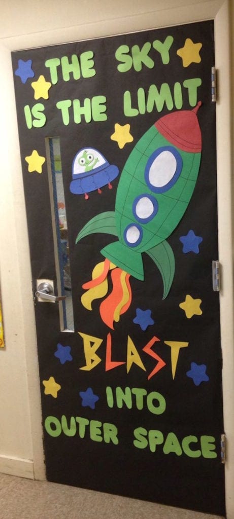 Spaced themed classroom door says the sky is the limit blast into outer space with a rocketship and an alien ship on it.