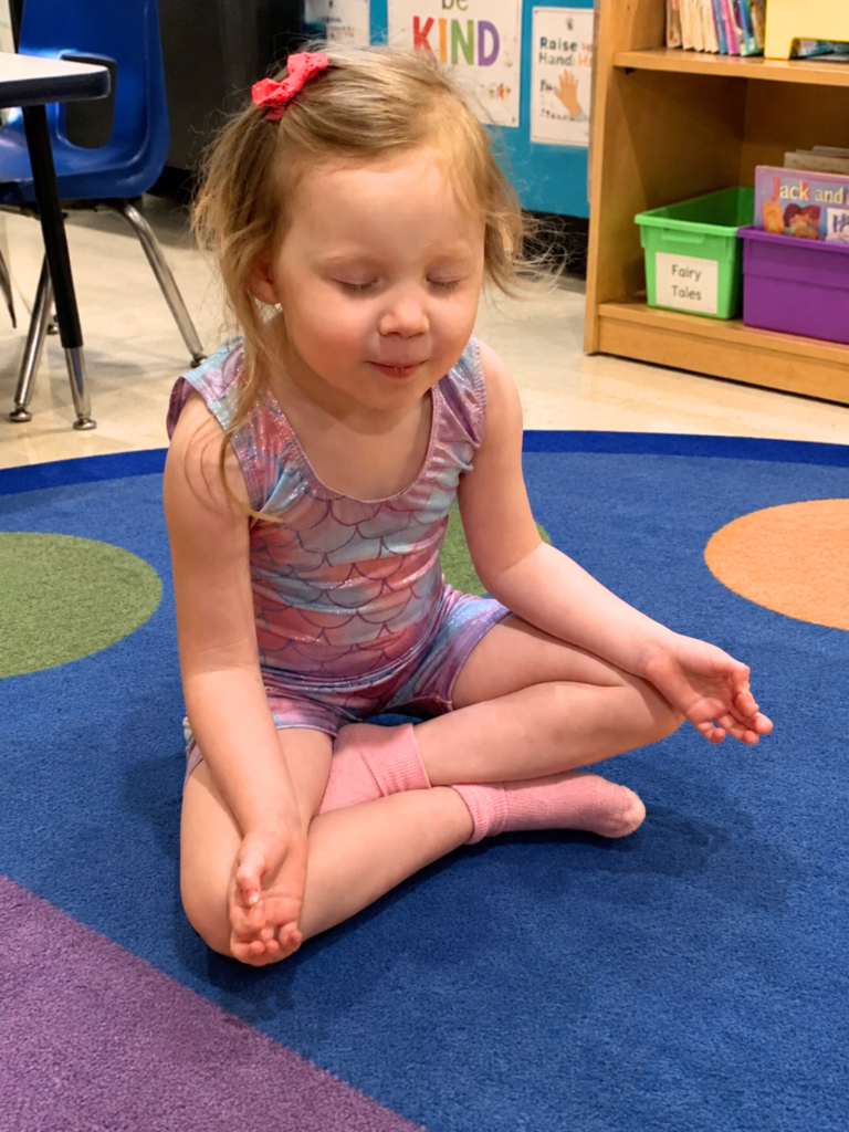 an image of a student closing their eyes on the carpet and taking a sound focus break