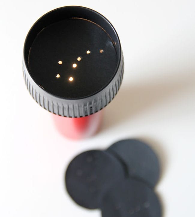 Star projector made from a flashlight covered on the light surface by a black construction paper disc with holes poked into it to represent a constellation in this example of one of many space activities for kids