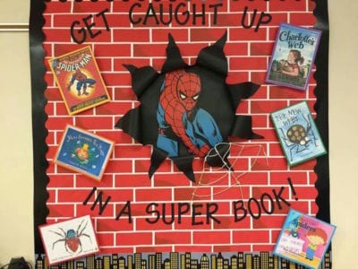 Poster of a brick wall with Spiderman breaking through it and words Get caught up in a super book!