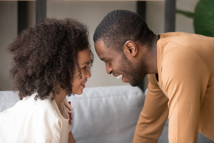 A little girl and a man are seen staring at eachother.