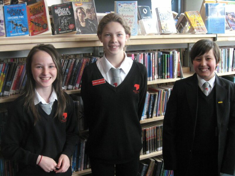 student librarians standing in front of a bookcase
