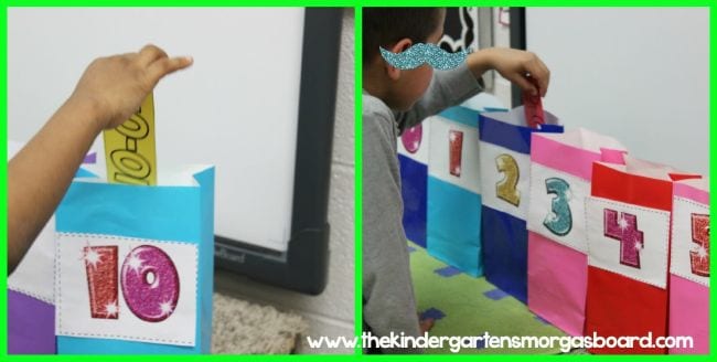 A student's hand places a subtraction flash card into a colorful bag with the correct number written on it