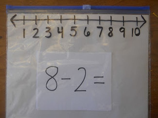 A ziploc bag with a number line drawn at the top in sharpie with a subtraction problem written on an index card inside the bag 