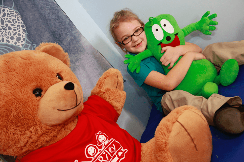 First grade girl hugging a stuffed animal.