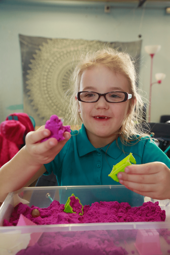 First grade girl playing with kinetic sand.