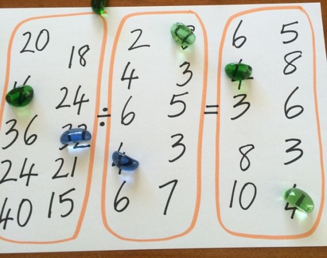 Three sections of a white board with numbers written in each and markers on some numbers (Teaching Division)