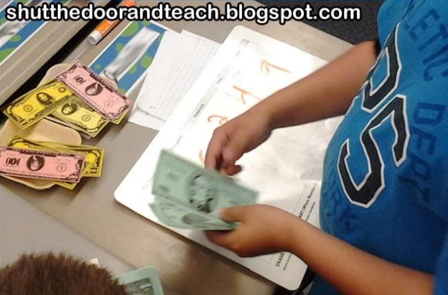 Student counting play money into piles