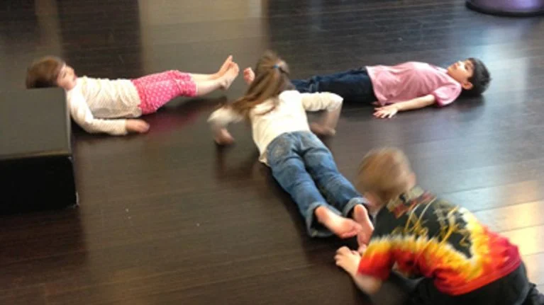 Students lying on the floor forming the letter "T" as an example of team building activities for kids. 