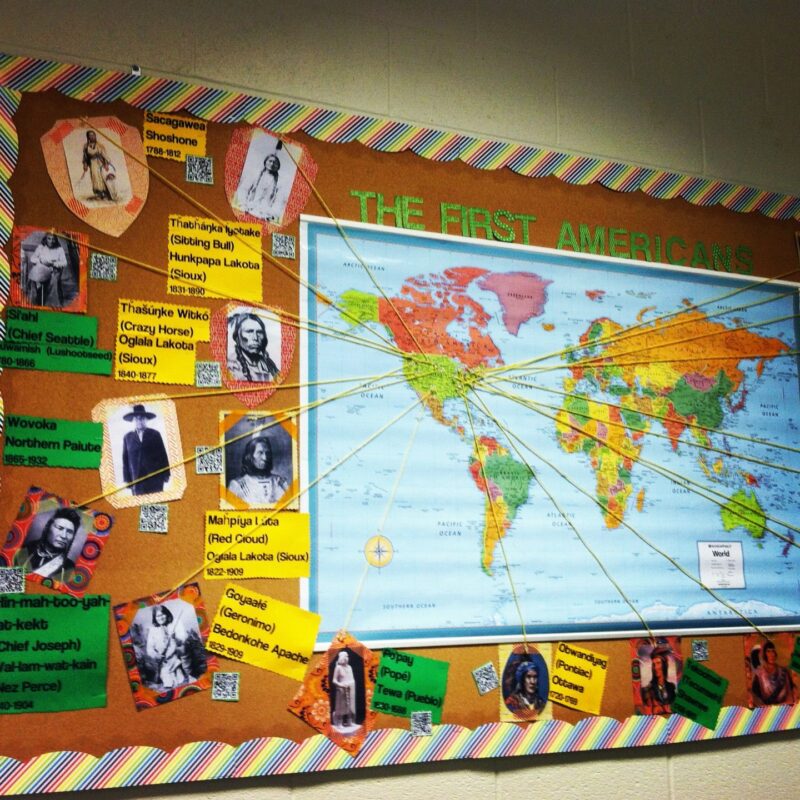 October bulletin board ideas like this one show a map with the text "The First Americans." Images of various native americans and accompanying text is displayed to the left of the map. 