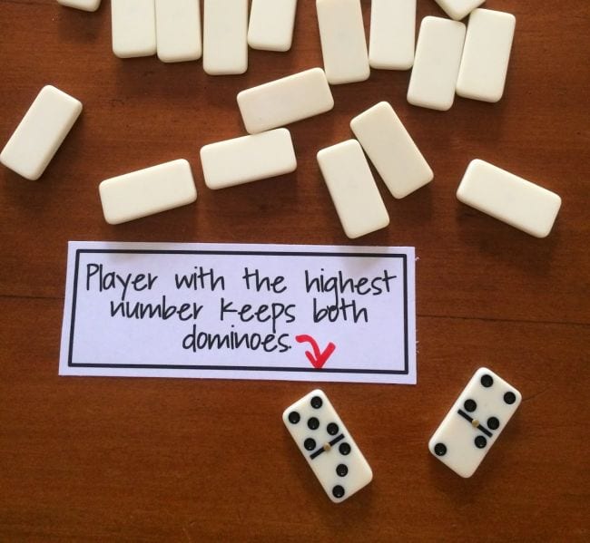 Upside-down dominos with two flipped over next to card reading "Player with the highest number keeps both dominos" (Third Grade Math Games)