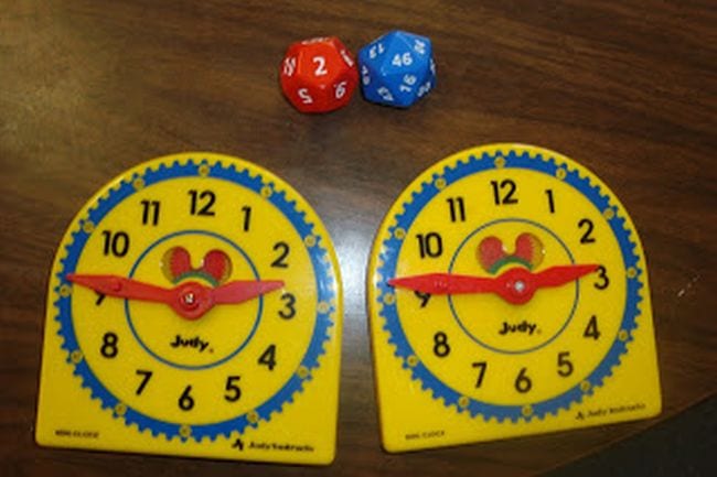 Two toy clocks next to a pair of polyhedral dice