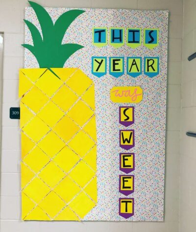 Bulletin board that reads 'this year was sweet.' A giant pineapple is on the side, and there is a colorful dotted background. 