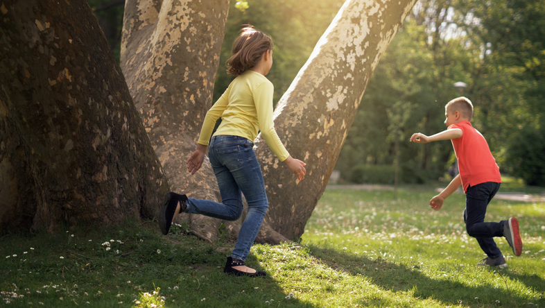 Two children are seen running outside in this example of tag games.