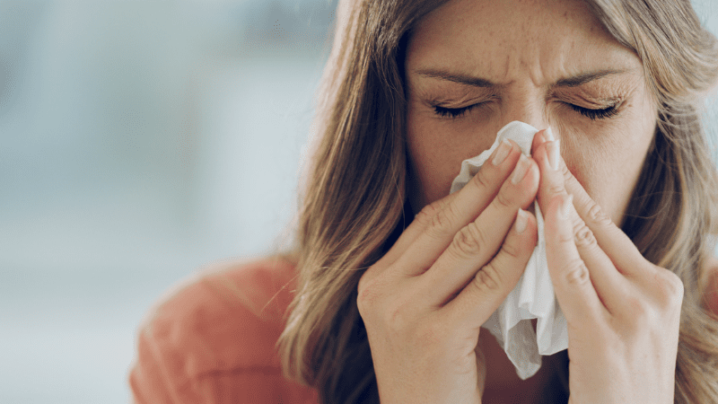 Woman sick with cold and blowing nose, as an example of a symptom of poor school air quality