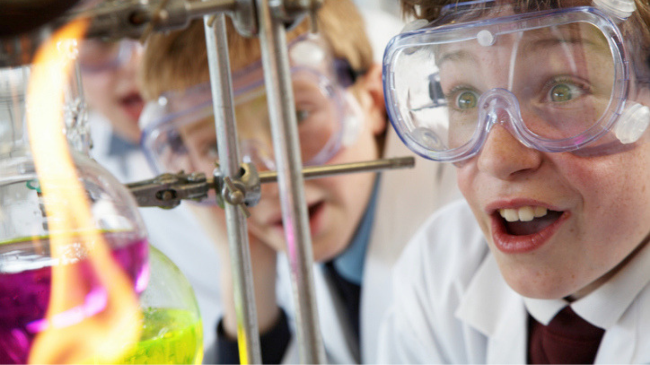 Excited students in lab coats and goggles looking at flame—STEM Activities for Middle School