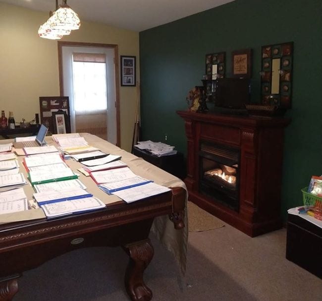 Pool table at teacher's home covered with file folders for remote learning