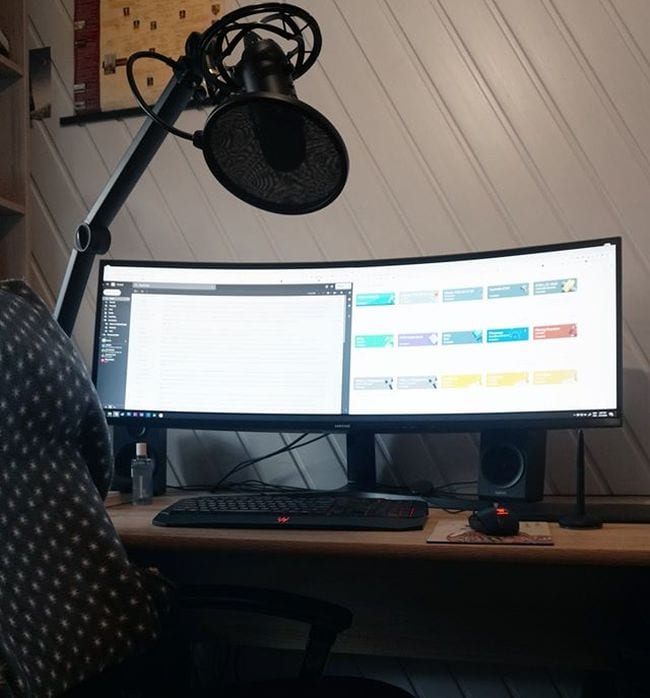 Curved screen and computer on desk with overhead microphone and light