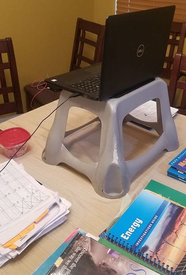 Plastic stool used to prop up laptop on light colored table in kitchen
