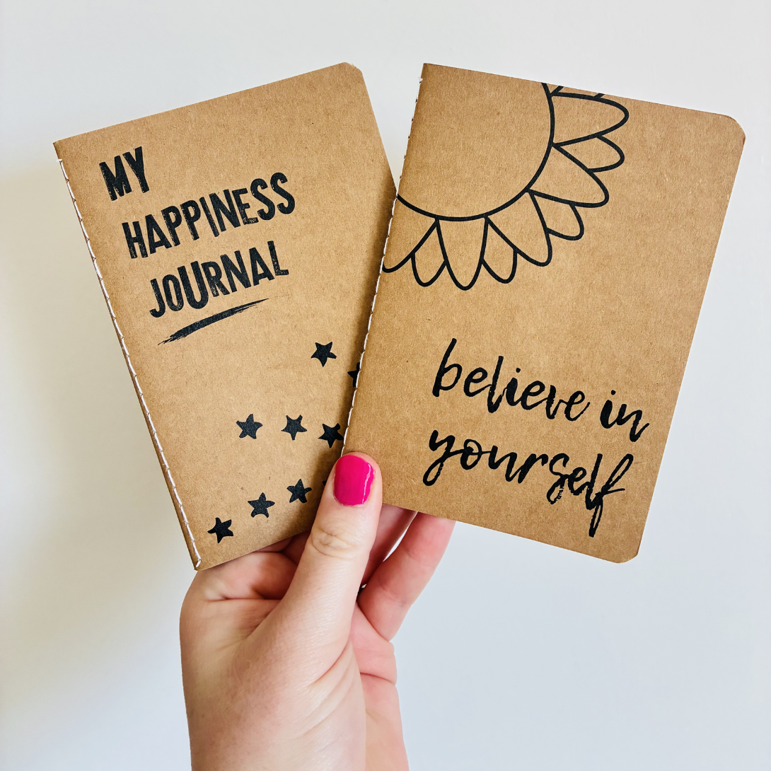 an image of a teacher holding up two small gratitude journals