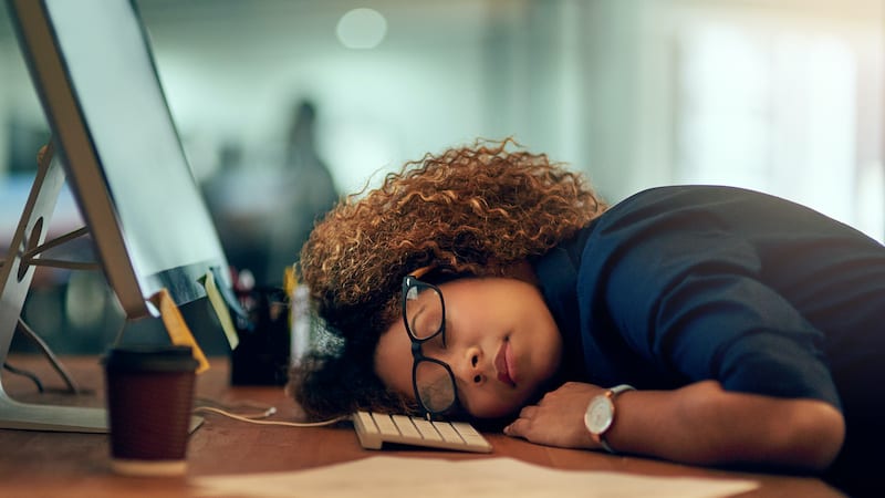 An exhausted young businesswoman sleeping at her desk during a late night at work.