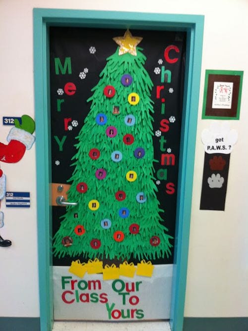Classroom door with a Christmas tree made of green paper handprints, decorated with ornaments with pictures of students