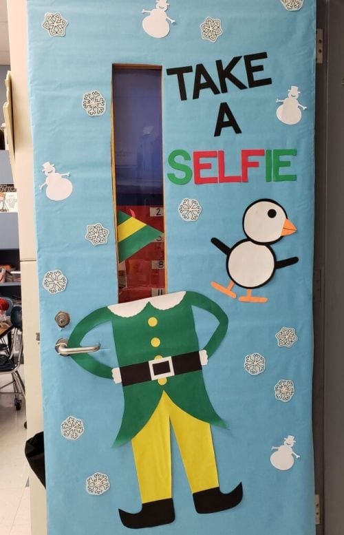 A classroom door is decorated with the body of an elf and it says Take a Selfie.