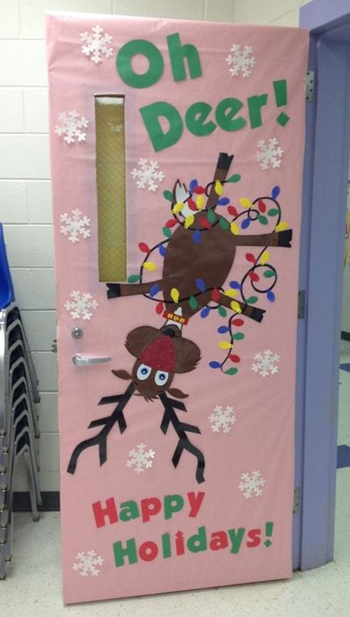 Classroom door with a reindeer hanging upside down wrapped in Christmas lights reading "Oh Deer!"