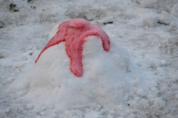Baking soda volcano with red lava erupting out of a pile of snow for a winter science experiment 