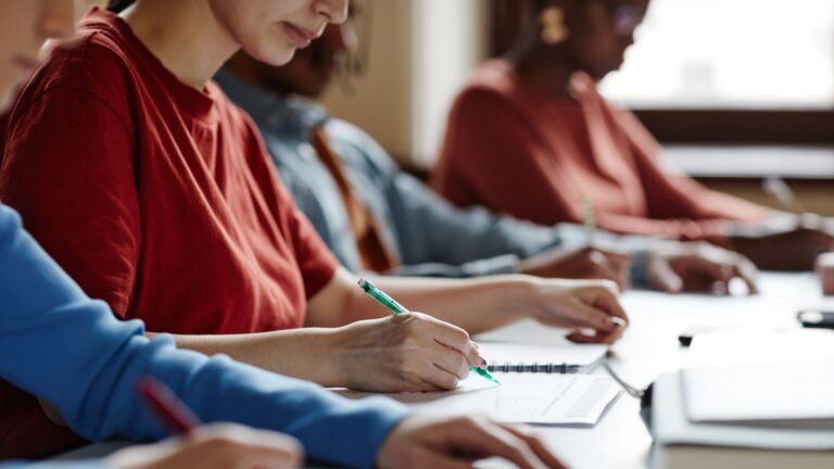 Photo of a class with students working by hand where a teacher can teach without phones
