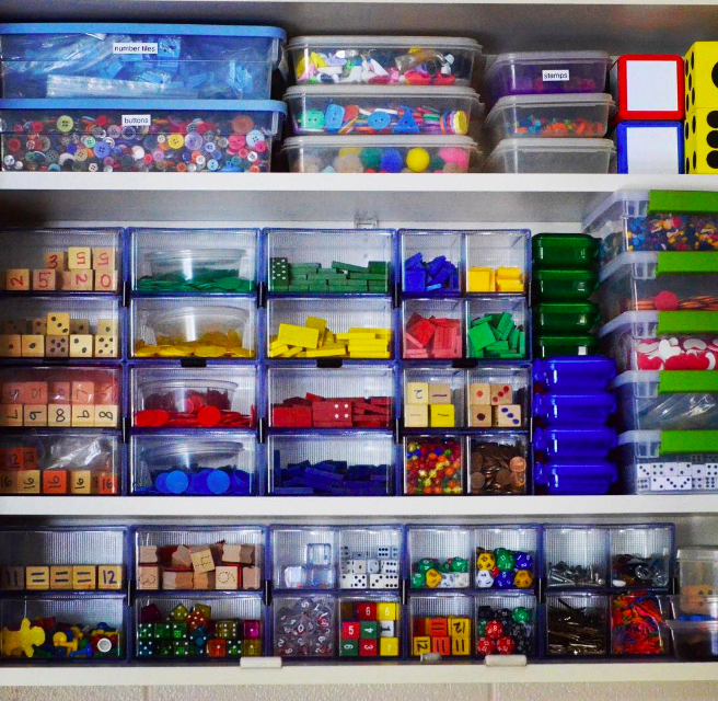 Shelves filled with plastic bins of classroom supplies as an example of teacher organization