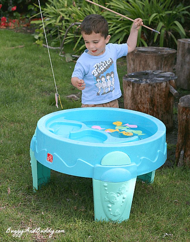 Child using a wood fishing pole to catch foam numbered fish in a kiddie pool
