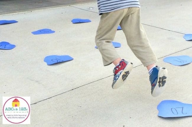 Student jumping around on construction paper puddles labeled with numbers (Active Math Games)