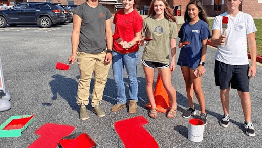 Students painting the concrete in this example of pep rally activities