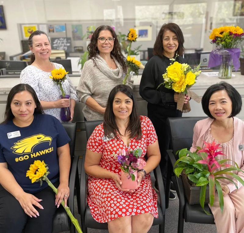 A group of school administrative professionals holding flowers