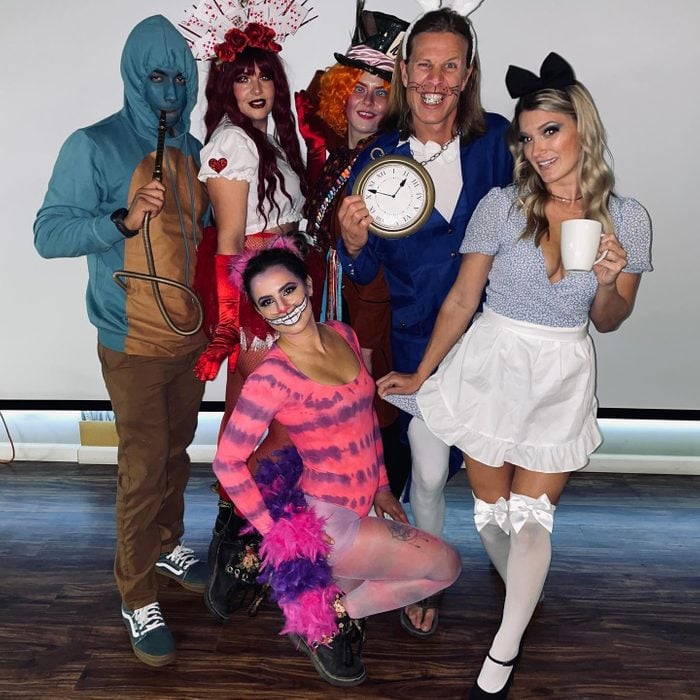 Six adults are shown dressed as various characters from Alice in Wonderland.