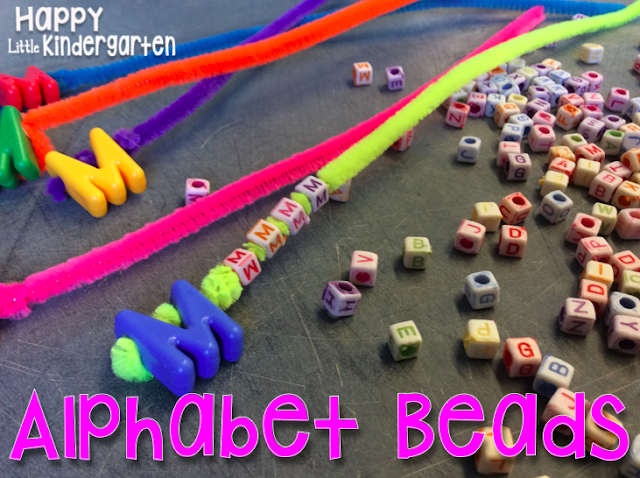 Colorful pipe cleaners strung with a large "M" bead beside smaller alphabet bead on a table as an example of alphabet activities