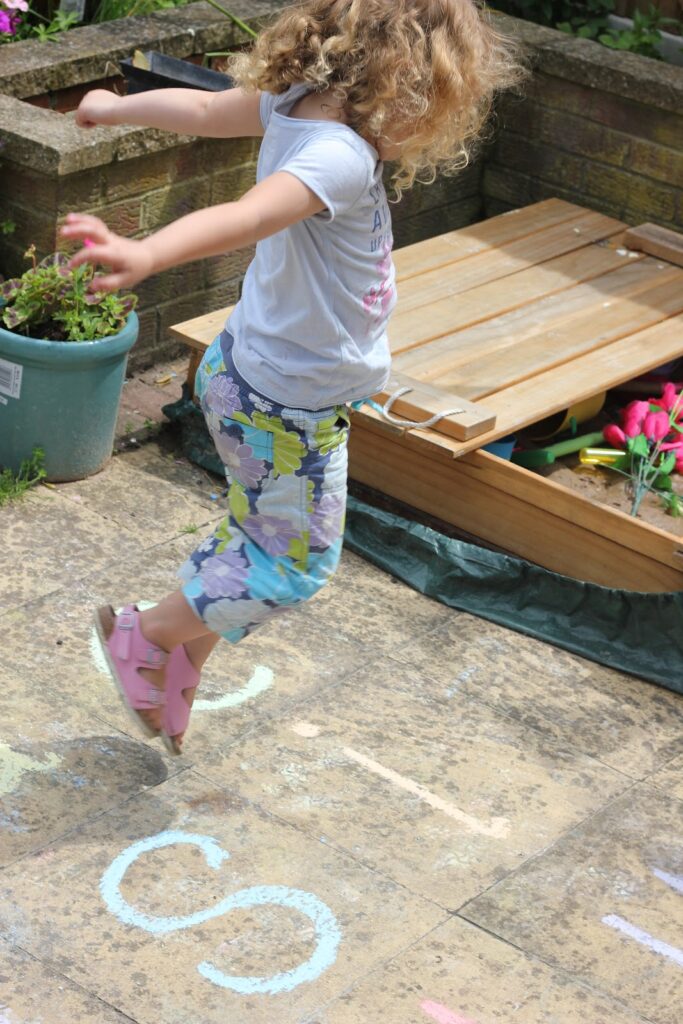 Girl jumping on chalk letters
