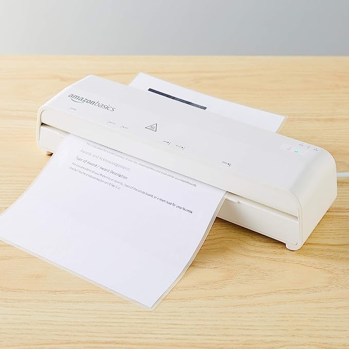 Amazon Basics laminator on table with paper rolling through.