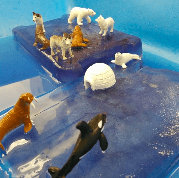 Frozen ice blocks, arctic animal figurines, and water in a sensory table for classroom sensory play