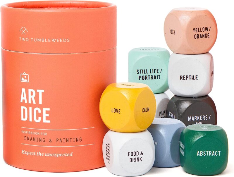 An orange container says Art Dice on it. There are large different colored dice that have different objects, words, and colors written on the sides of them.