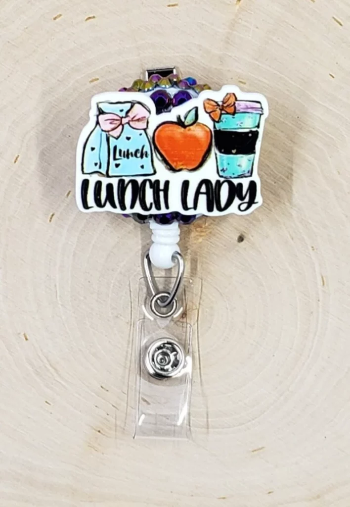 A cute badge holder says Lunch Lady and has a cartoon bagged lunch, apple, and coffee cup.