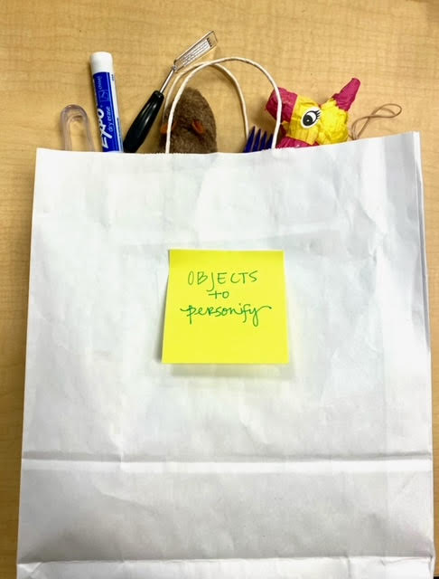 White paper bag filled with objects to describe with personifcation.